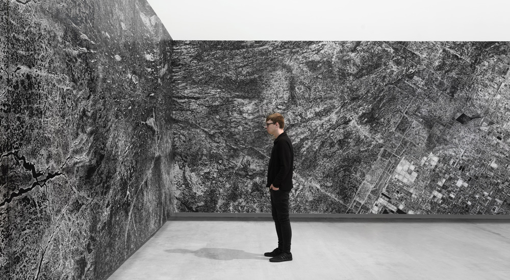 person looking a large wall installation composed black and white aerial photography